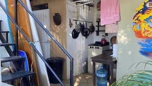 Une cuisine compacte équipée d’une cuisinière à gaz, de casseroles suspendues et d’un distributeur d’eau.