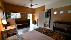 Une chambre à coucher comprenant un lit, un bureau, une chaise, une armoire, un ventilateur de plafond et une fenêtre.