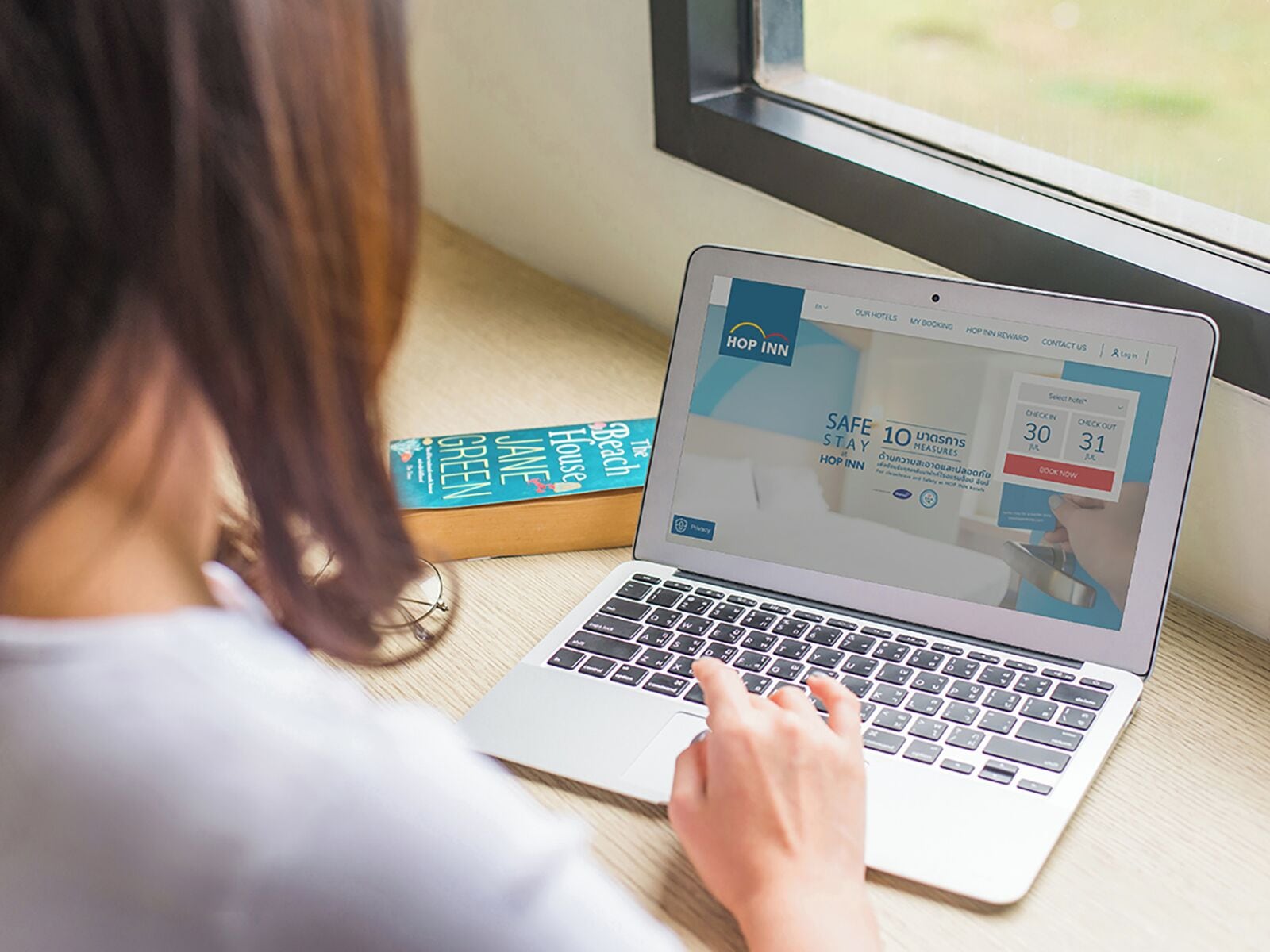 Un portatile mostra un sito web per prenotare un hotel con una promozione 'Safe Stay'.