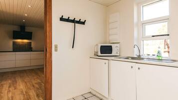 A kitchen with white cabinets, a microwave, a sink, and a window.