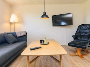 A living room with a sofa, a table, a TV, and a chair. - 4 Person Holiday Home in Ostervra (Østervrå)