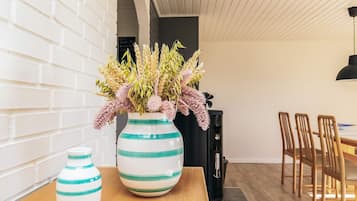 Uma sala de jantar com uma mesa de madeira, dois vasos listrados com flores e uma máquina de café preta.