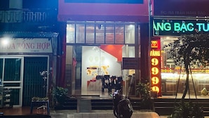 A hotel with a prominent sign reading "PHAM GIA HOTEL" and a neon sign advertising "VÀNG 99". - Pham Gia Hotel Ha Giang - by Bay Luxury (Ha Giang 1)