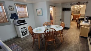 A compact kitchen with a dining area, featuring a microwave, a small refrigerator, and a wooden dining table with chairs.