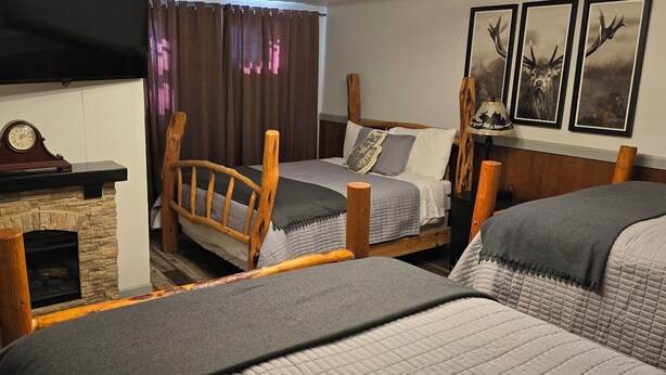 A cozy room with two beds, a fireplace, a television, and framed wildlife pictures.