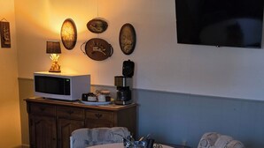 A cozy room with a microwave on a wooden cabinet, a coffee maker, and decorative wall art.