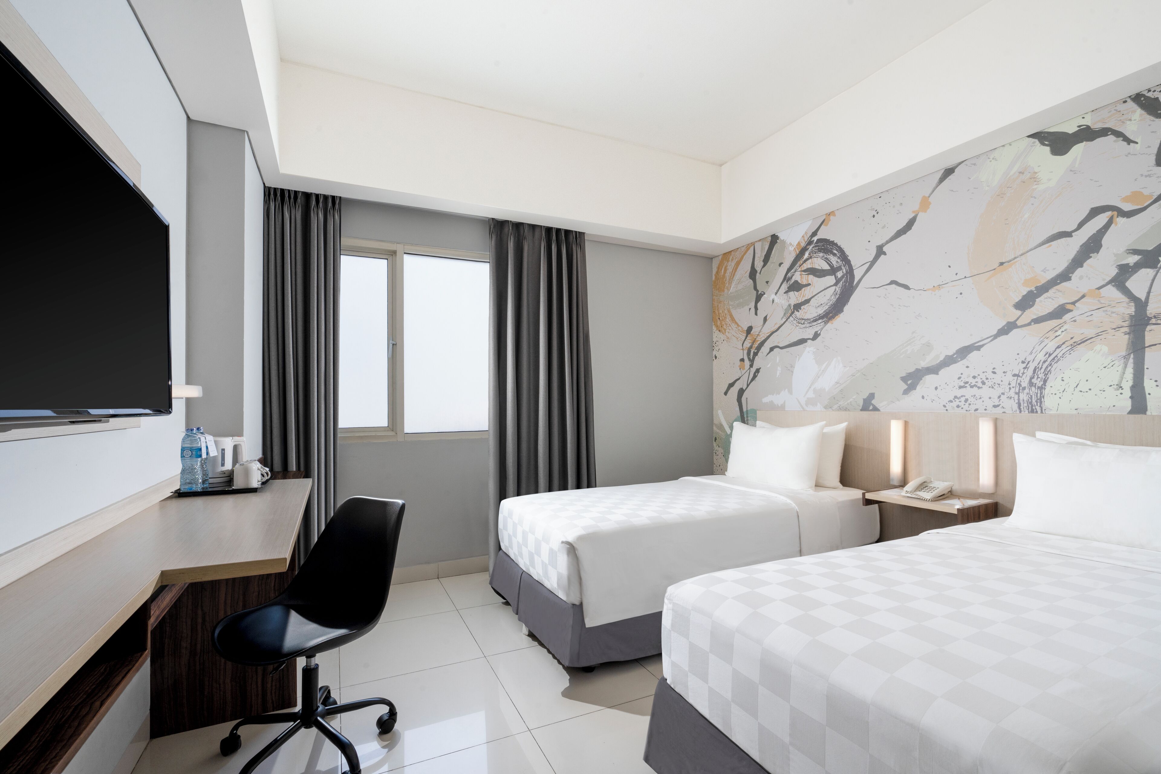 Une chambre d’hôtel avec deux lits, un bureau, une chaise, une télévision et une fenêtre avec des rideaux.