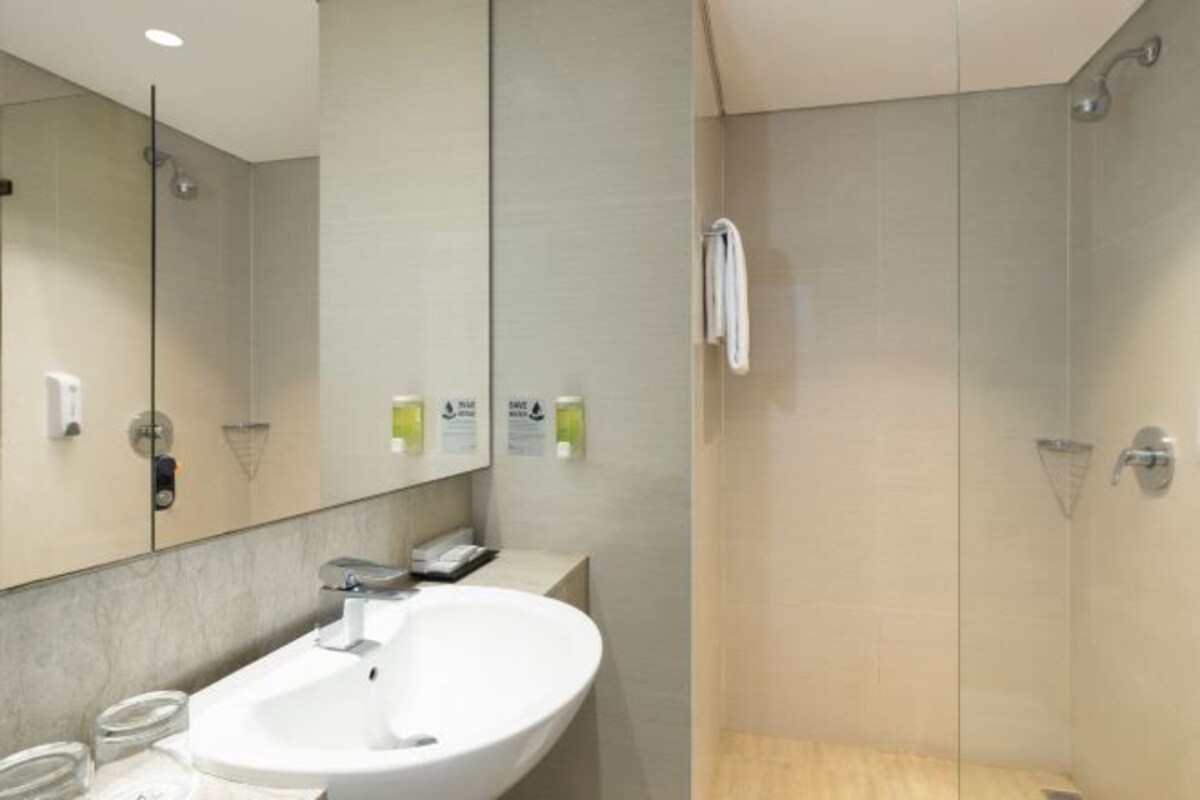 Een moderne badkamer met een grote spiegel, een wastafel en een douche.