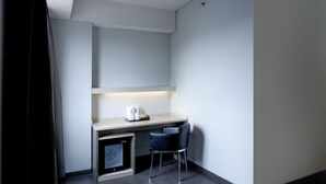 A small, modern kitchenette with a countertop, a coffee maker, and a chair. - Swiss-Belexpress Cideng (Jakarta)