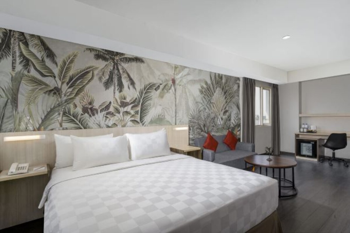 Een moderne hotelkamer met een groot bed, een bureau, een stoel en een klein tafeltje.