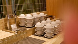 A display of white ceramic cups and saucers, a coffee machine, and a small sign indicating 'air mineral mineral water'. - Swiss-Belexpress Cideng (Jakarta)