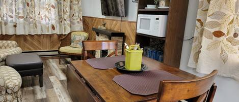 Un comedor con mesa de madera, sillas y un recipiente amarillo con cubiertos.