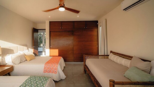 Une chambre d’hôtel avec deux lits, un ventilateur de plafond, un appareil de climatisation et une vue sur l’extérieur.