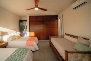 Une chambre d’hôtel avec deux lits, un ventilateur de plafond, un appareil de climatisation et une vue sur l’extérieur.