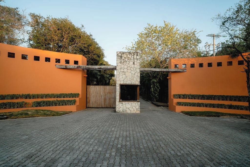Een geplaveid toegangspad met een stenen zuil en oranje muren.