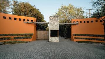 Een geplaveid toegangspad met een stenen zuil en oranje muren.