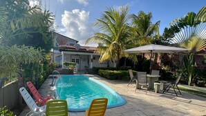A swimming pool with lounge chairs, a patio area, and a house with a tiled roof. - Bela Casa P Dos Carneiros cond.Beira Mar (Tamandaré)