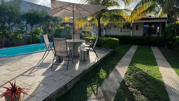 A patio area with a pool, outdoor seating, and palm trees. - Bela Casa P Dos Carneiros cond.Beira Mar (Tamandaré)