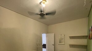 A room with two beds, a ceiling fan, a door, and a small shelf with books. - Bela Casa P Dos Carneiros cond.Beira Mar (Tamandaré)
