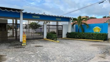 A gated entrance with a blue canopy labeled "VISITANTES" and "CONDOMINIOS".