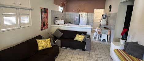Un espacio habitable compacto con kitchenette, un conjunto de sofás y un comedor.