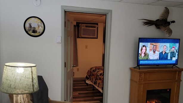 Un salon équipé d’un téléviseur, d’une cheminée, d’une lampe, d’un canapé et d’un escalier menant à une autre pièce.