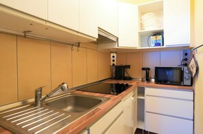 Cozinha compacta com pia, fogão, micro-ondas e cafeteira.