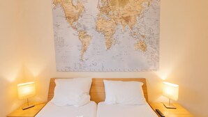 A double bed with white bedding, two bedside lamps, and a world map on the wall. - Appartement Peter in Freyung im Bayerischen Wald (Freyung)