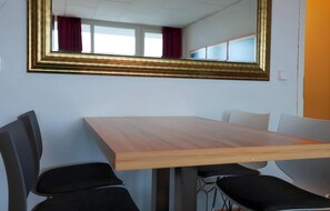 A conference room with a wooden table, black chairs, and a large mirror on the wall. - Appartement Peter in Freyung im Bayerischen Wald (Freyung)