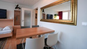 A hotel room with a bed, a TV, a dining table, and a large mirror. - Appartement Peter in Freyung im Bayerischen Wald (Freyung)