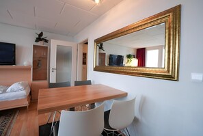 A hotel room with a bed, a TV, a dining table, and a large mirror. - Appartement Peter in Freyung im Bayerischen Wald (Freyung)