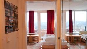 A hotel room with a bed, a desk, a chair, and a view of the mountains. - Appartement Peter in Freyung im Bayerischen Wald (Freyung)