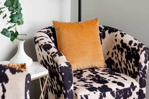A chair with a cow print pattern and a mustard-colored pillow.