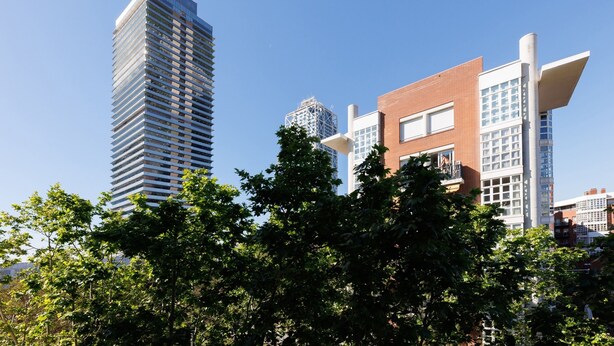 A modern high-rise building with a unique architectural design, surrounded by trees and other buildings.