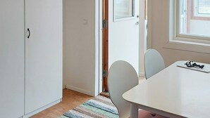 Een kamer met een witte tafel, twee stoelen, een gestreept vloerkleed en een raam met uitzicht.