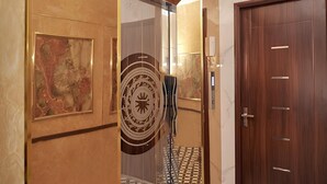 Un couloir avec une porte en bois, une œuvre d’art encadrée et un panneau décoratif mural.
