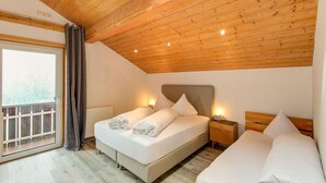 A bedroom with a wooden ceiling, a large window with curtains, and two beds with white linens. - Holiday Home in the Silvretta-montafon ski Area (Sankt Gallenkirch)