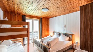 A wooden cabin room with bunk beds, a single bed, a small bedside table, and a bathtub. - Holiday Home in the Silvretta-montafon ski Area (Sankt Gallenkirch)