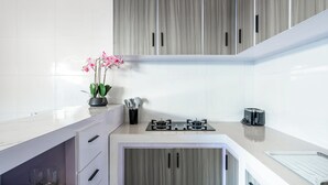 A modern kitchen with grey cabinets, a white countertop, and a gas stove.