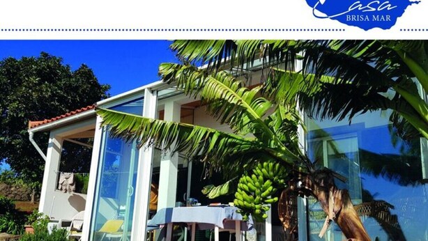 A modern house with a glass facade, a balcony, and a tropical garden. - Holiday Home Casa Brisa Mar in Prazeres (Calheta)