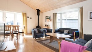 Un vaste espace de vie doté d’un plafond en bois, d’une cheminée, d’un canapé, d’une table basse et d’un téléviseur.