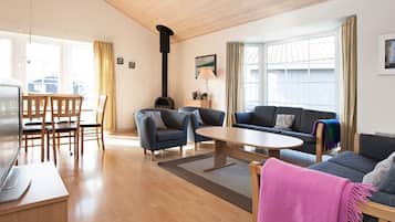 A spacious living area with a wooden ceiling, a fireplace, a sofa, a coffee table, and a TV.