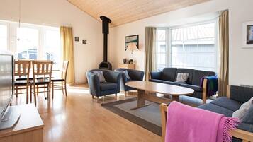 A spacious living area with a wooden ceiling, a fireplace, a sofa, a coffee table, and a TV.