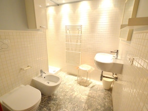 Une salle de bain comprenant des toilettes, un bidet, un lavabo et un porte-serviettes.