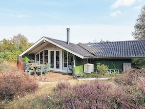 A rustic house with a sloped roof, a chimney, and a covered patio area with outdoor furniture. - 6 Person Holiday Home in Albaek (Aalbaek)