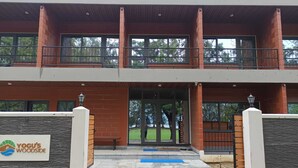 Un edificio de dos pisos con fachada de ladrillo, amplias ventanas y una entrada porticada.