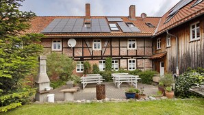 A traditional half-timbered house with solar panels, outdoor seating, and a garden.