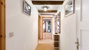 A hallway with wooden beams, white walls, and a carpeted floor.
