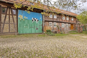 Il s’agit d’un bâtiment traditionnel doté d’une porte de garage verte, d’un sol pavé et d’une structure à deux étages avec des fenêtres apparentes et une porte en bois.
