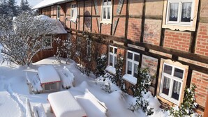 A traditional half-timbered building with snow-covered ground and a wooden bench.